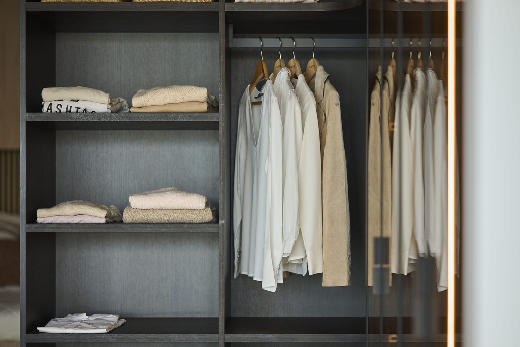Dressing sur mesure avec penderie pour vêtements et étagères en bois foncé dans un showroom