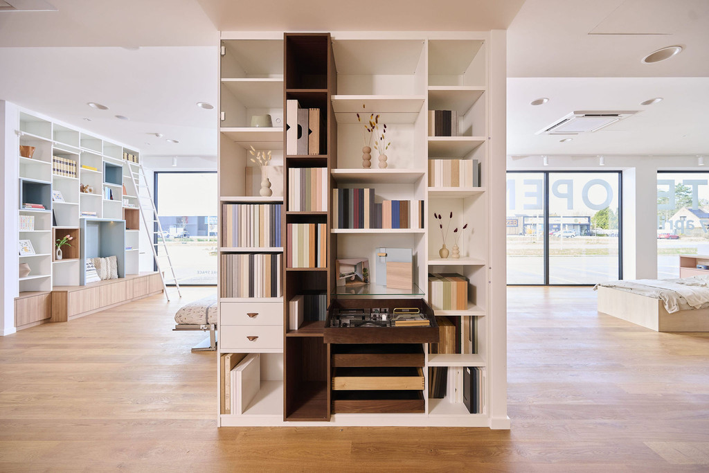 Placard sur mesure utilisé comme séparateur avec niches ouvertes, casier à vin et rangements dans un showroom moderne
