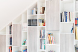 Bibliothèque sur mesure avec étagères ouvertes et fermées, conçue pour un rangement optimisé sous un toit mansardé.