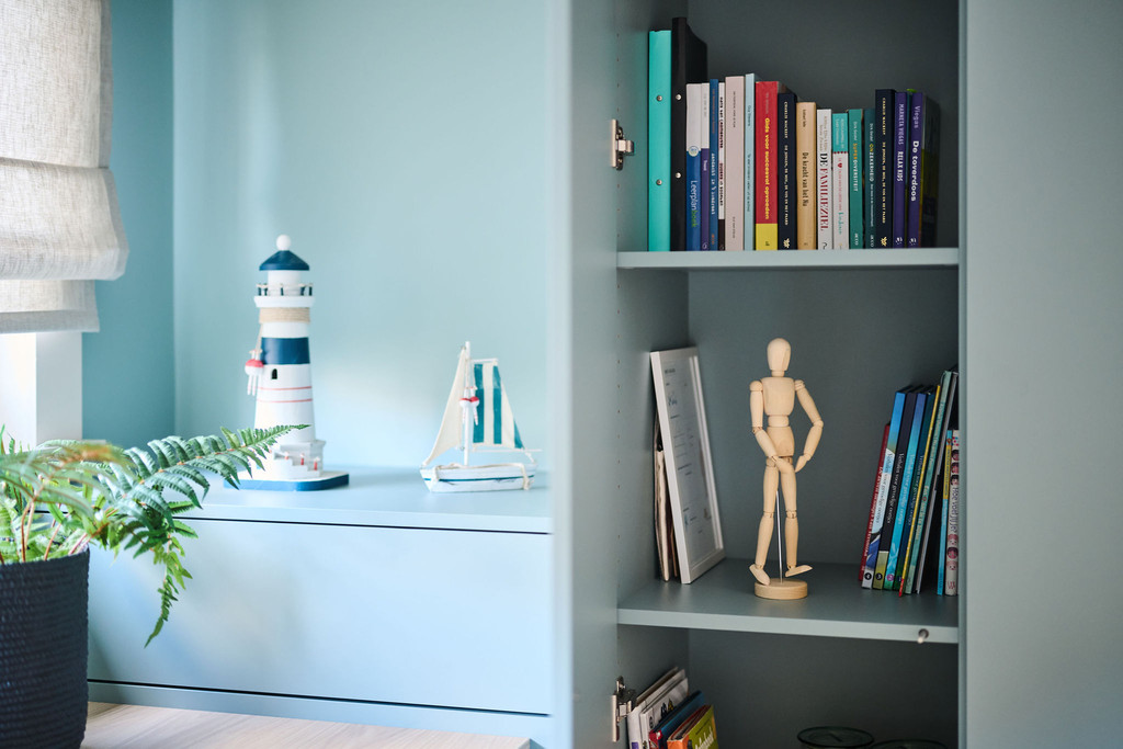 Niche ouverte dans un bureau bleu sur mesure avec livres objet déco et accessoires marins