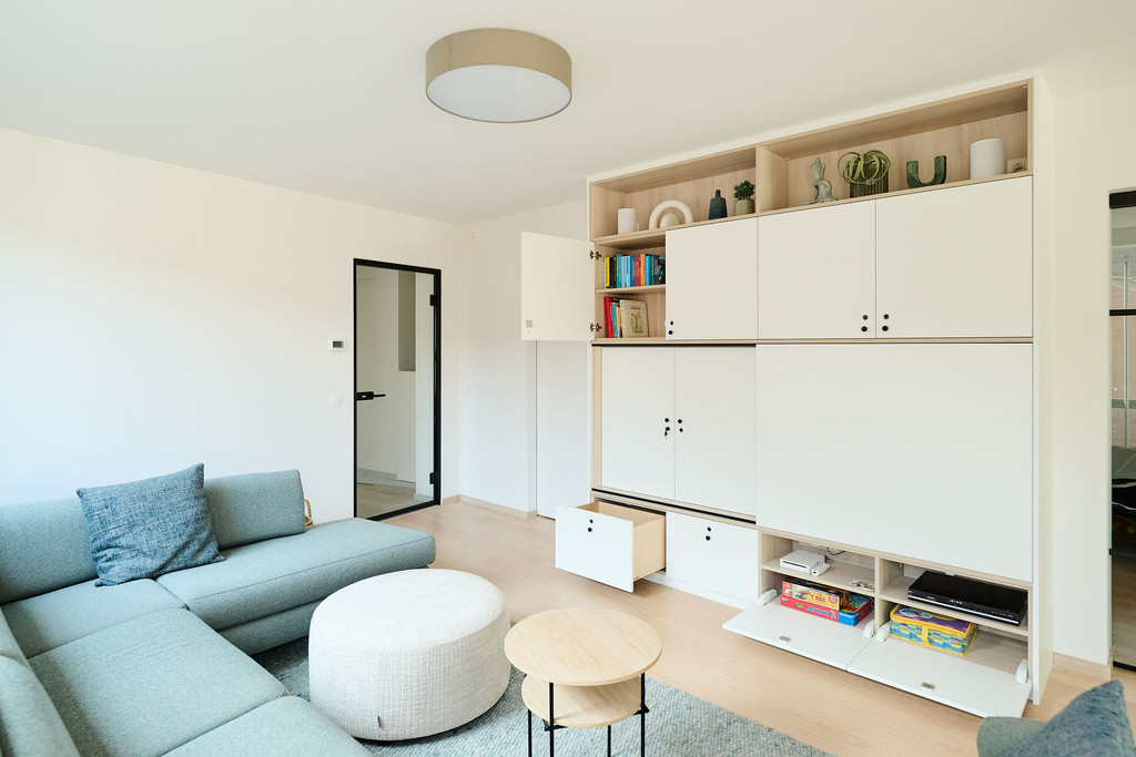 Meuble TV ouvert avec livres, jeux et jouets dans un salon lumineux