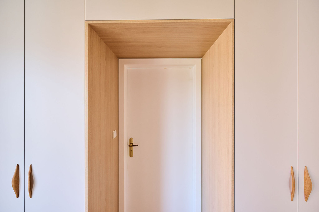 Porte discrètement intégrée dans un placard sur mesure avec encadrement en bois dans un intérieur moderne