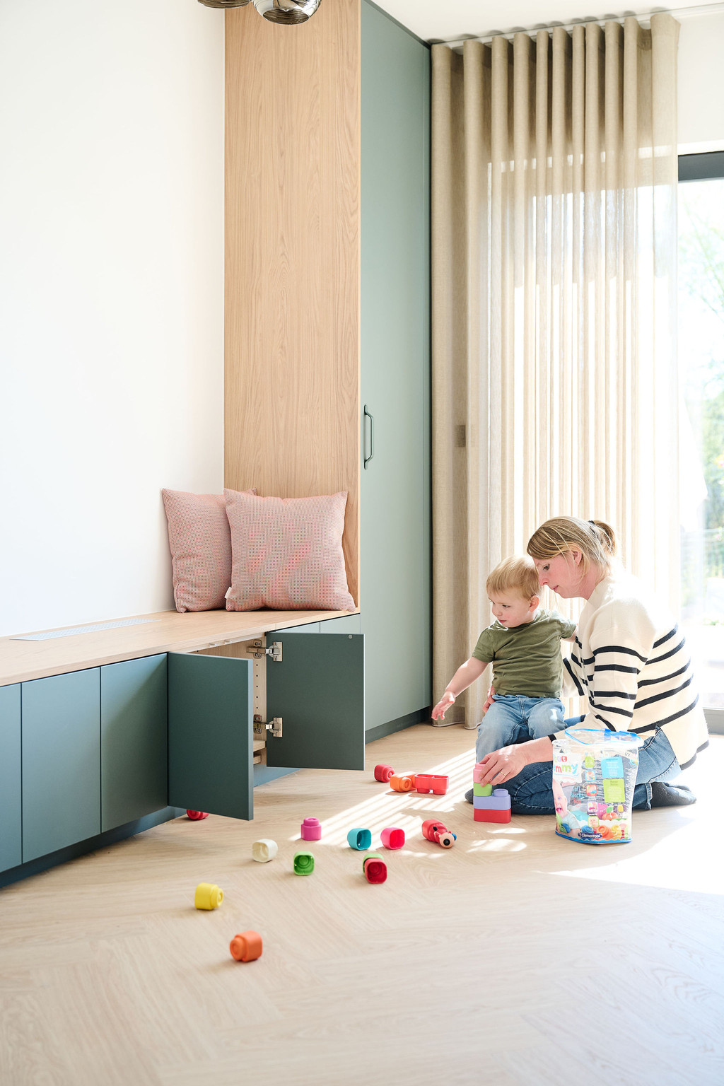 Maman jouant avec son enfant devant un banc de rangement vert avec portes ouv