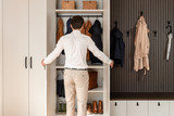 Man opent een op maat gemaakte vestiairekast met jassen, tassen en schoenen in een strakke inkomhal.