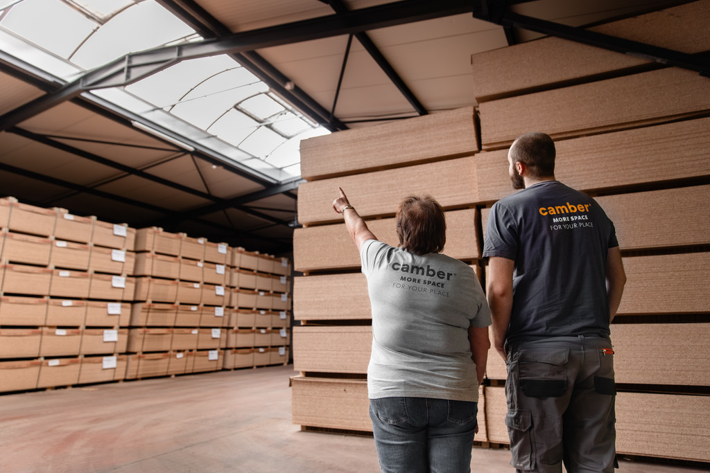 Collaborateurs Camber dans un entrepôt de panneaux de bois certifiés, illustrant l'engagement de l'entreprise en faveur de la durabilité et d'une gestion responsable des matériaux.