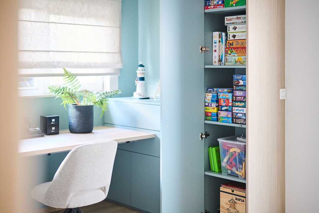 Open kast in blauw bureau met gezelschapsspellen speelgoed en opbergruimte naast werkblad