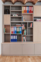 Bibliothèque sur mesure avec étagères ouvertes et rangements fermés, idéale pour un bureau organisé avec classeurs et livres.