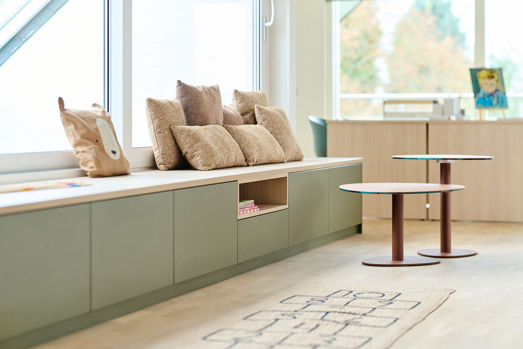 Banquette verte sur mesure sous fenêtre avec coussins beiges et coffre de rangement ouvert