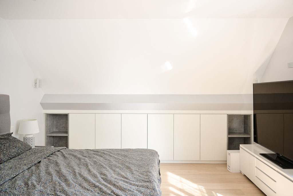 Meuble blanc fermé sous pente dans la chambre à coucher de Morgane