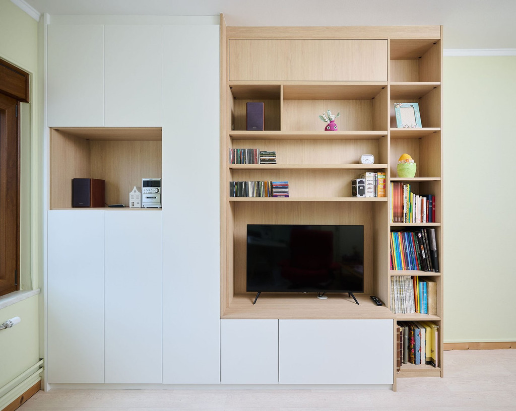 Op maat gemaakte wandkast met tv-nis, boekenplanken en gesloten kasten in een lichte leefruimte