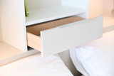 Detail van een opklapbed met geïntegreerde lade voor extra opbergruimte naast het bed.