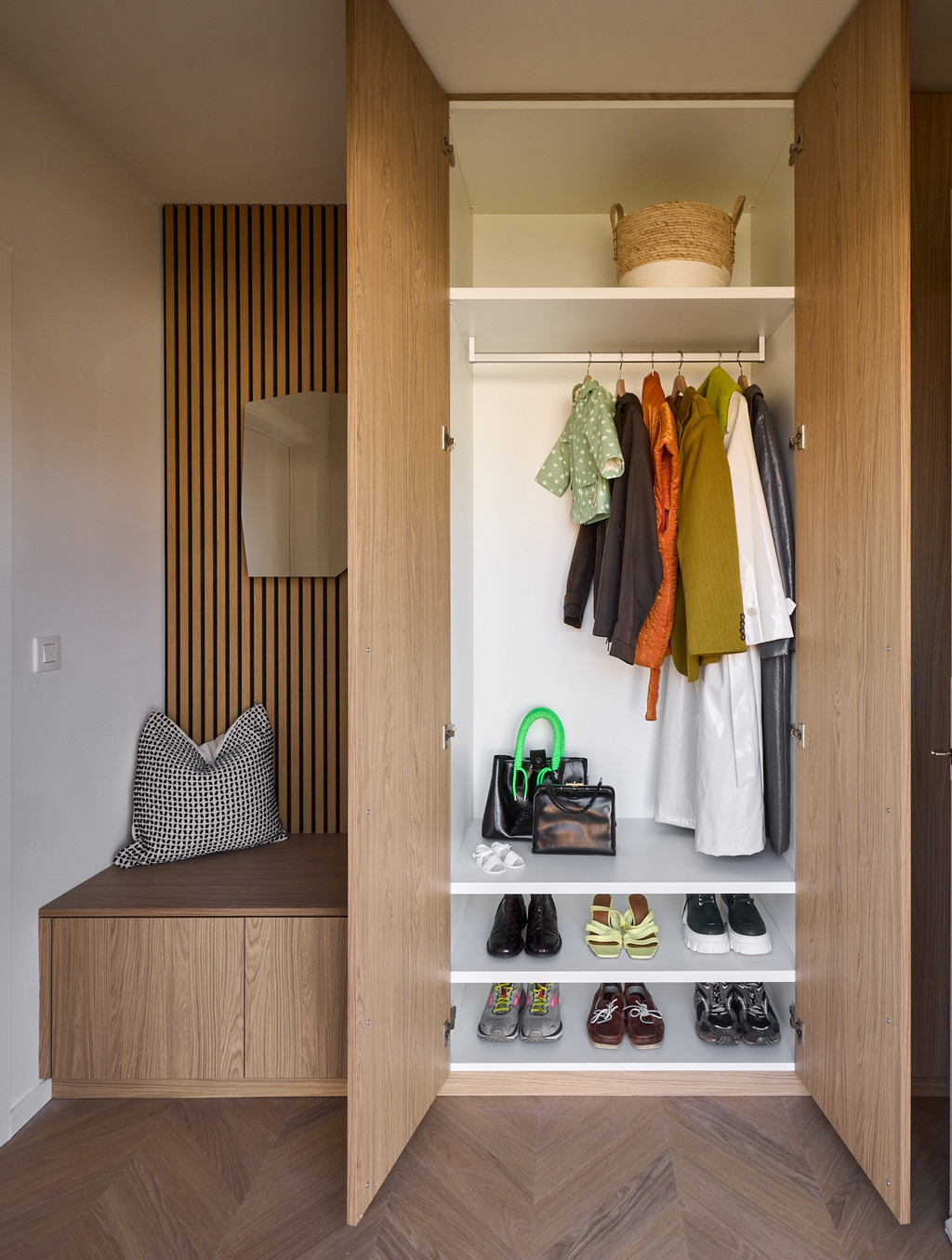 Vestiairekast op maat in hout met open hangruimte, schoenenrekken en geïntegreerde zitbank met houten lattenwand, voor een praktische en warme inkomhal