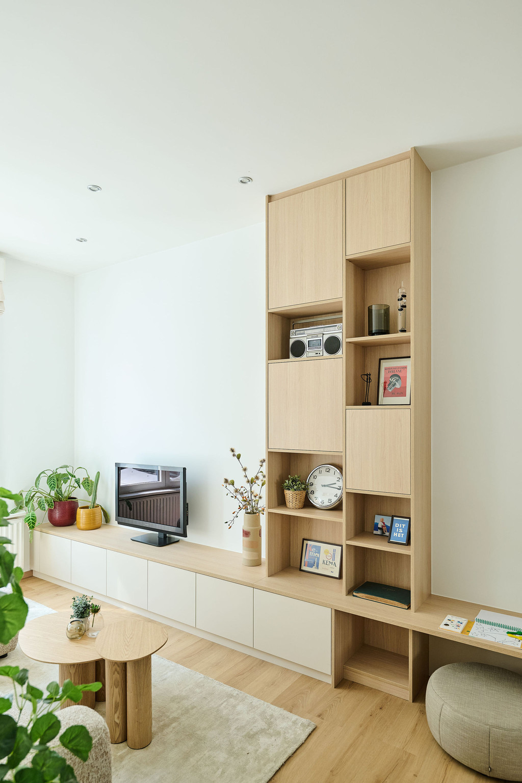 Wandmeubel op maat met open houten vakken en gesloten opbergruimte, voor een combinatie van decoratie en functionaliteit in een lichte ruimte