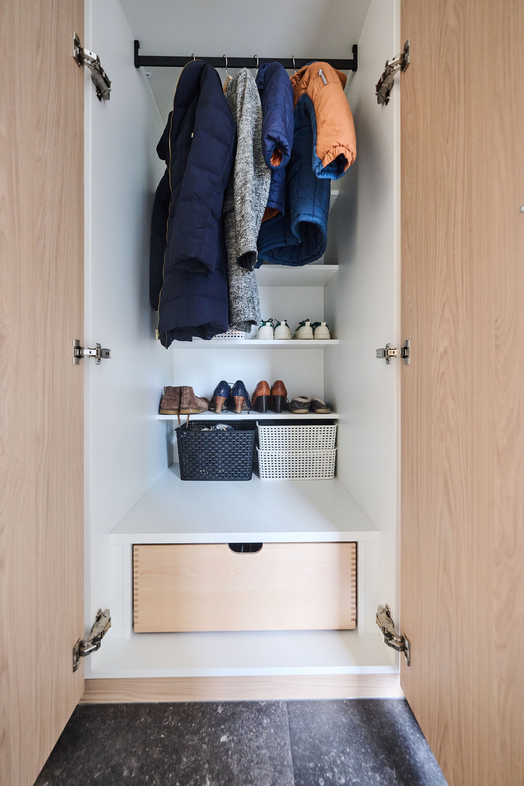 Armoire vestiaire en bois ouverte avec espace penderie chaussures sur étagères et tiroir fermé en bas