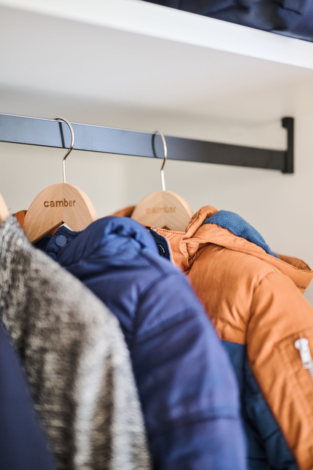 Verschillende jassen aan houten kapstokken met zwarte draagstang