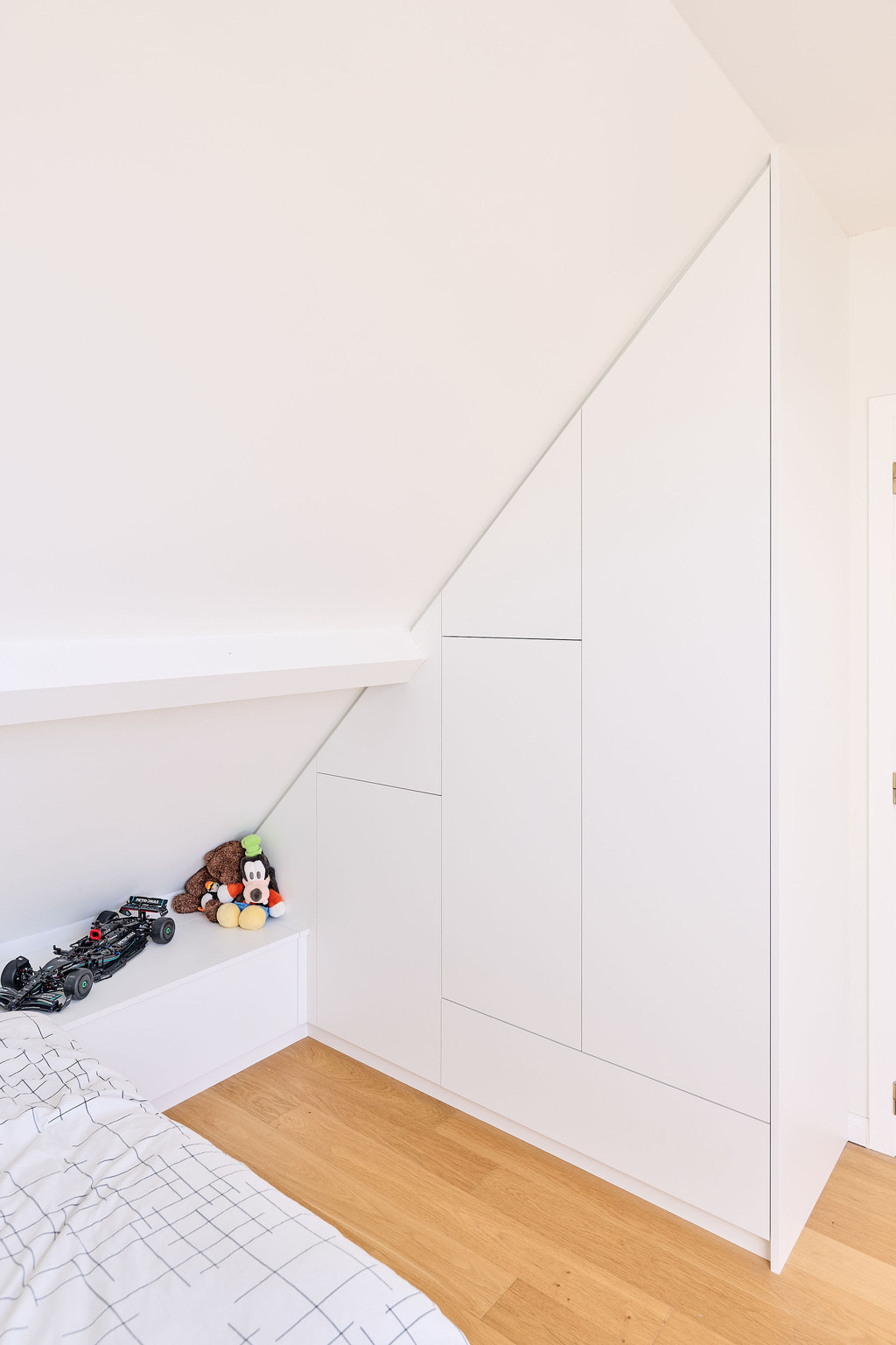 Placard sur mesure intégré sous pente avec banquette et rangements dans une chambre d’enfant