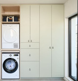 Buanderie Camber sur mesure avec machine à laver et sèche-linge intégrés en colonne, placards fermés sur mesure et espaces de rangement supplémentaires dans un aménagement épuré et fonctionnel