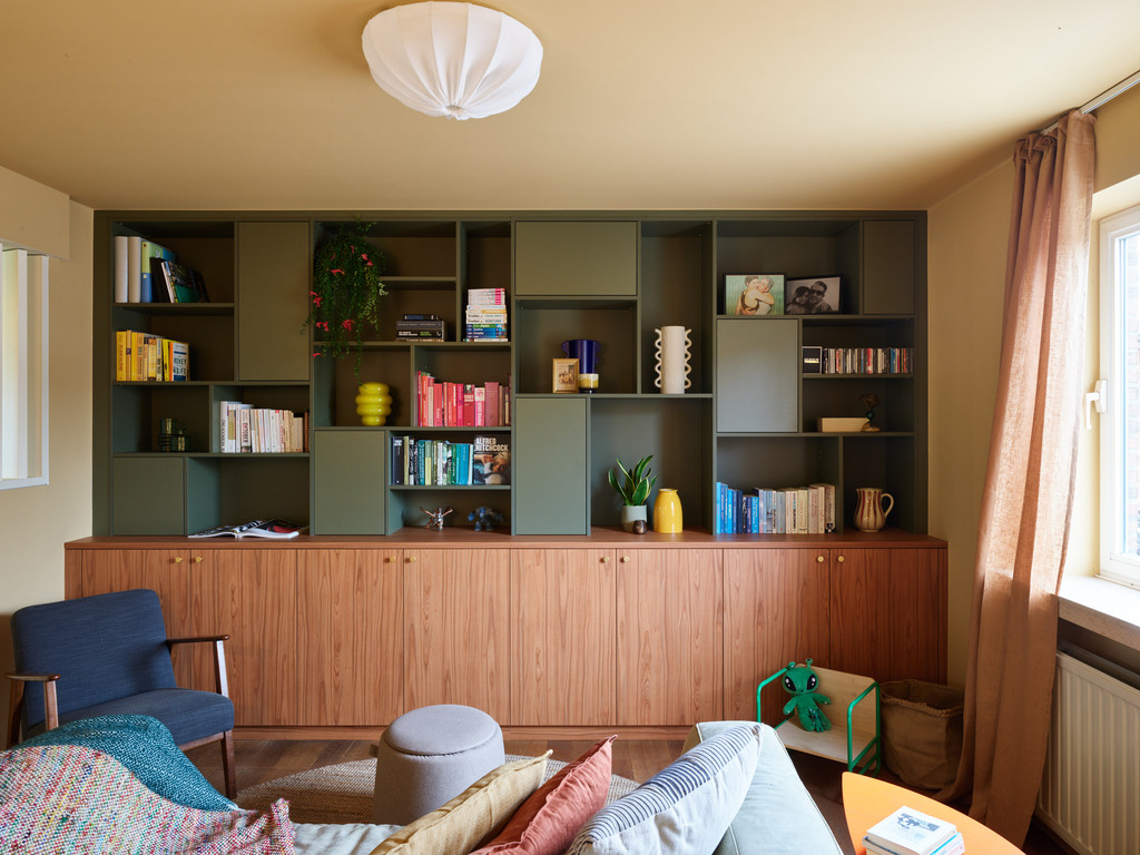 Meuble mural vert et bois dans le salon avec livres et objets déco