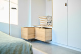 Détail d'un meuble de chambre d'enfant avec tiroirs en bois et coussins décoratifs.