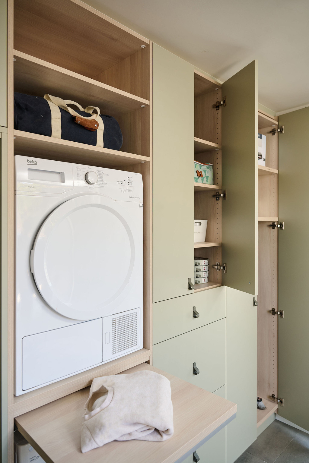 Buanderie Camber sur mesure avec sèche-linge intégré en colonne, niches ouvertes pour le rangement et placards fermés dans un aménagement pratique et soigné