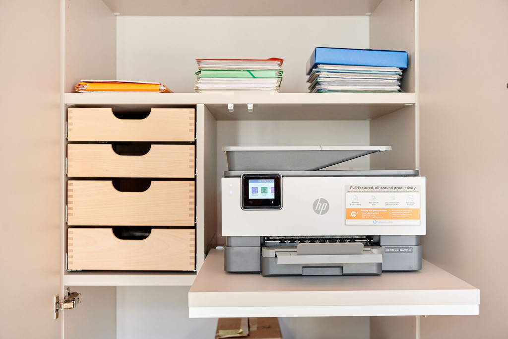 Op maat gemaakt bureau met geïntegreerde opbergkast, houten lades en een uitschuifbaar plateau voor een printer.