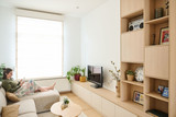 Meuble tv sur mesure en bois clair avec niches ouvertes et rangements bas, femme lisant sur le canapé