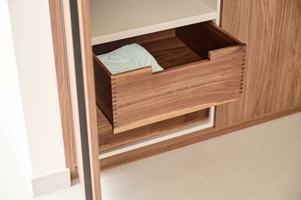 Houten lade in een op maat gemaakte vestiairekast, open getrokken voor extra opbergruimte.