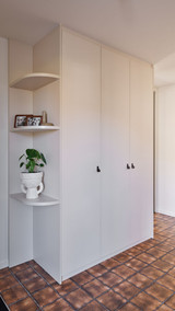 Armoire vestiaire blanche sur mesure avec niches arrondies dans un hall d’entrée avec carrelage brun