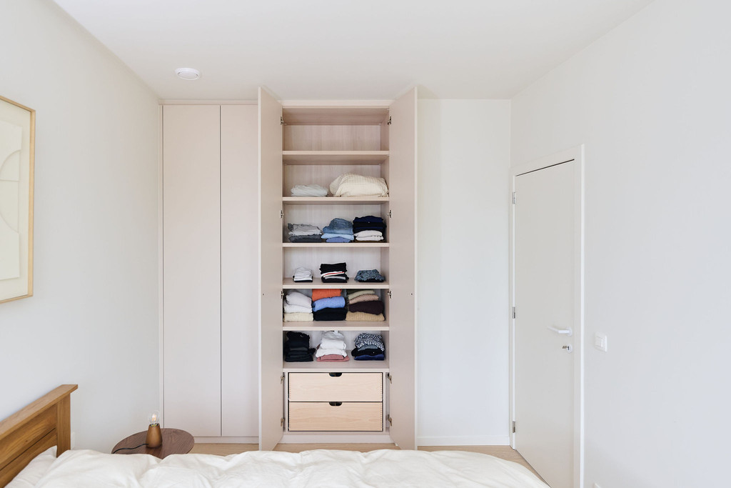 Armoire sur mesure ouverte avec étagères et tiroirs en bois dans une chambre