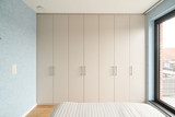 Placard haut sur mesure avec portes en tons clairs et poignées élégantes, intégré dans une chambre pour un rangement optimal, réalisé par Camber