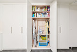 Armoire de buanderie sur mesure avec étagères de rangement pour produits de nettoyage, paniers à linge, planche à repasser et cintres.