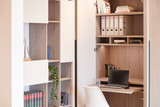 Bureau sur mesure avec rangement intégré, étagères ouvertes et espace de travail minimaliste avec ordinateur, offrant un aménagement fonctionnel.