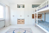Chambre d'enfant avec lit superposé et mobilier sur mesure, armoire et étagères pour rangement.