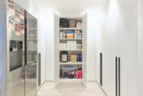 Armoire blanche sur mesure pour buanderie avec étagères organisées contenant divers produits de nettoyage et accessoires.