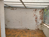 Mur en briques partiellement peintes avec carrelage orange dans un espace avant rénovation