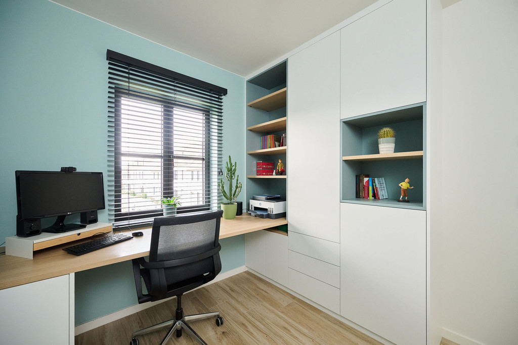 Bureau sur mesure avec bibliothèque intégrée, rangements fermés et niches ouvertes, avec mur vert d’eau et grand bureau en bois.