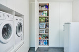Placard blanc sur mesure dans une buanderie avec étagères contenant des produits ménagers, boîtes et accessoires divers.