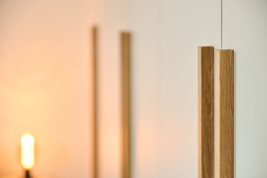 Gros plan sur les poignées en bois d’une armoire sur mesure beige dans une chambre éclairée