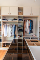 Grand dressing ouvert sur mesure avec îlot vitré et vêtements rangés sur étagères et cintres
