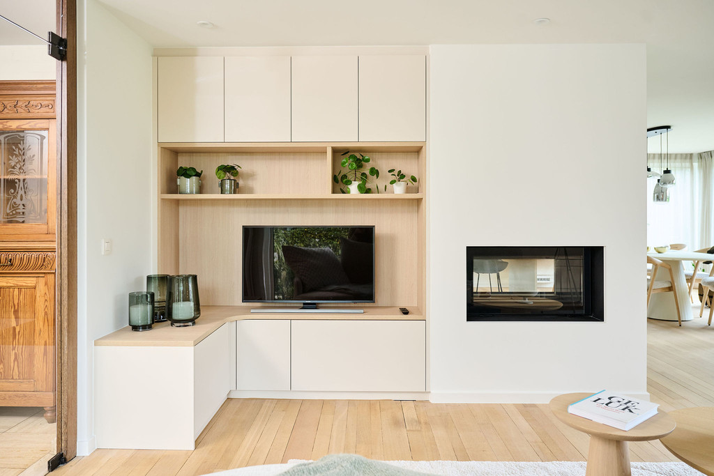 Meuble TV sur mesure en bois clair avec rangements fermés et étagères décorées de plantes