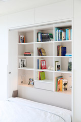 Opklapbed met ingebouwde boekenkast, boeken netjes opgevouwen in de planken, met een opbergvak onderaan.