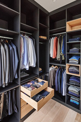 Dressing ouvert sur mesure en forme de U avec finition noire, tiroirs en bois et rangements ouverts pour vêtements et accessoires.