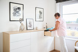 Anne opent een lade van een witte ladekast op maat in de slaapkamer, afgewerkt met een houten bovenblad