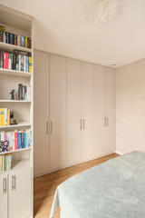 Dressing sur mesure en pleine hauteur avec portes en tons clairs et poignées élégantes, offrant un rangement maximal dans une chambre moderne, réalisé par Camber