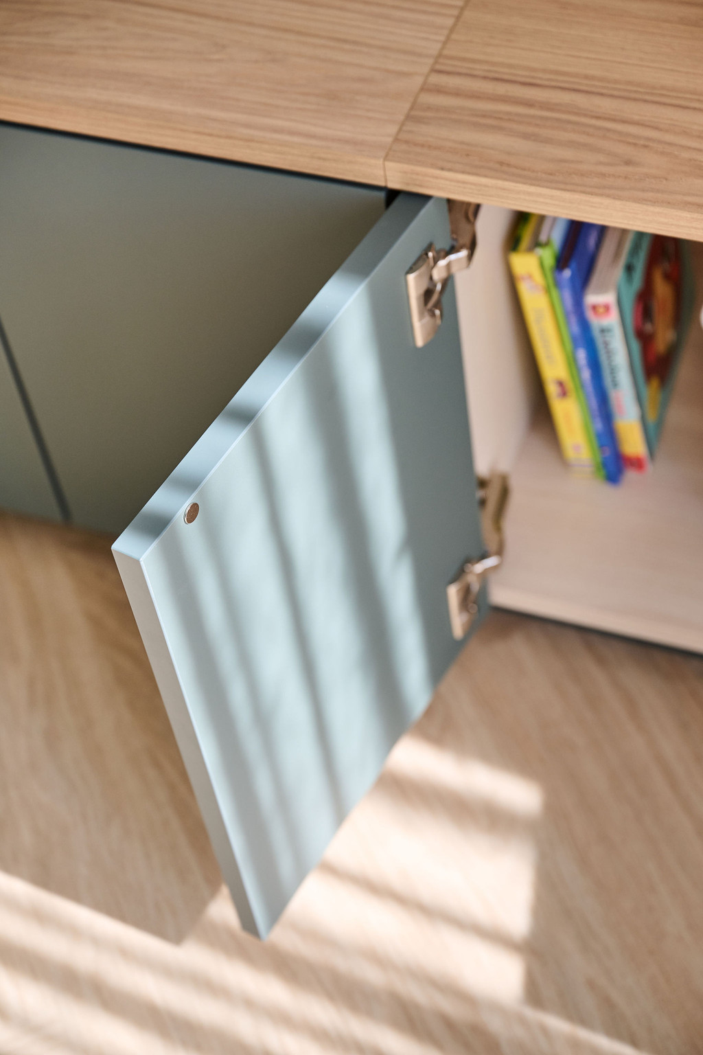 Meuble bas sur mesure avec portes ouvertes et coussins roses sur l’assise en bois clair