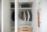 Intérieur d'un vestiaire fermé sur mesure, avec étagères et tringle pour suspendre des vêtements, et tiroirs en bas pour le rangement.