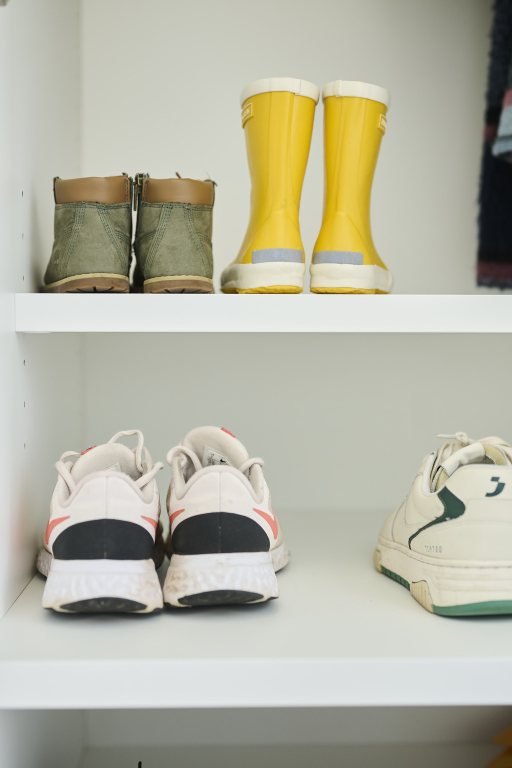 Twee niveaus met kinderschoenen en sneakers in een witte vestiairekast