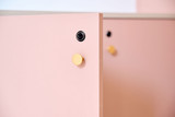 Gros plan sur porte d’armoire rose avec poignée dorée et serrure noire