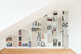 Bibliothèque sur mesure avec étagères ouvertes sous un toit mansardé, permettant un rangement esthétique et fonctionnel des livres
