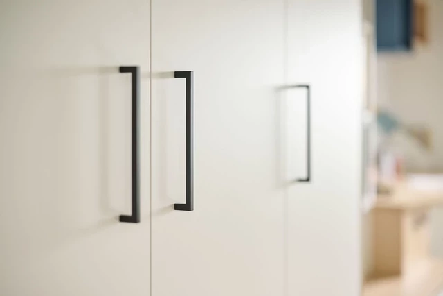 Détail des poignées noires minimalistes sur une armoire sur mesure pour une touche moderne et épurée.